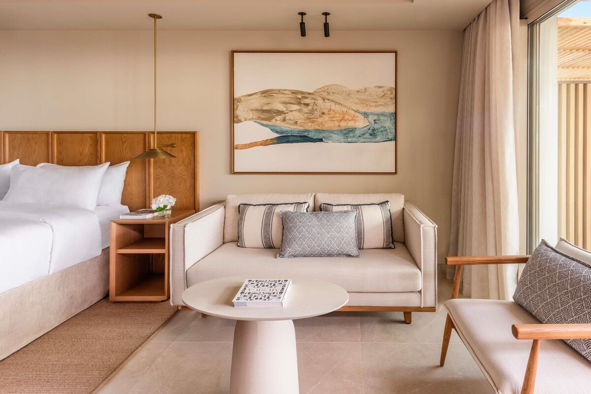 Une chambre d’hôtel avec un lit, un canapé, une table basse et un tableau au mur.
