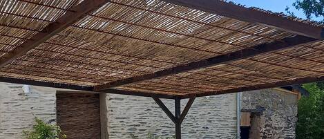 Un espace extérieur aménagé avec une table et des chaises, une pergola et un mur en pierre.