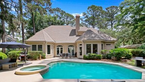 Une maison avec une piscine, du mobilier de jardin et un espace extérieur couvert.