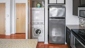 A compact kitchen with a stainless steel refrigerator, a built-in oven, and a microwave. - Stylish Top Floor Condo in Downtown Indianapolis, Mile Square Neighborhood  (Indianapolis)