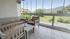 A balcony with a sofa and chairs, a table with a cup and saucer, and a clock on the wall.