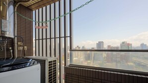 Une pièce dotée d’une grande fenêtre donnant sur un paysage urbain, d’un radiateur et d’un appareil de climatisation.