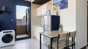 Une cuisine compacte équipée d’un lave-linge, d’une table à manger et de chaises.
