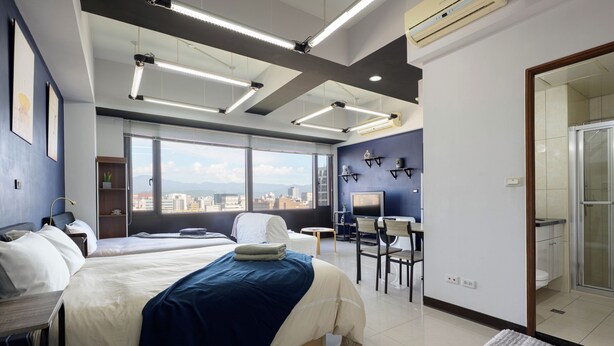 Une chambre d’hôtel moderne avec deux lits, un bureau et une vue sur la ville.