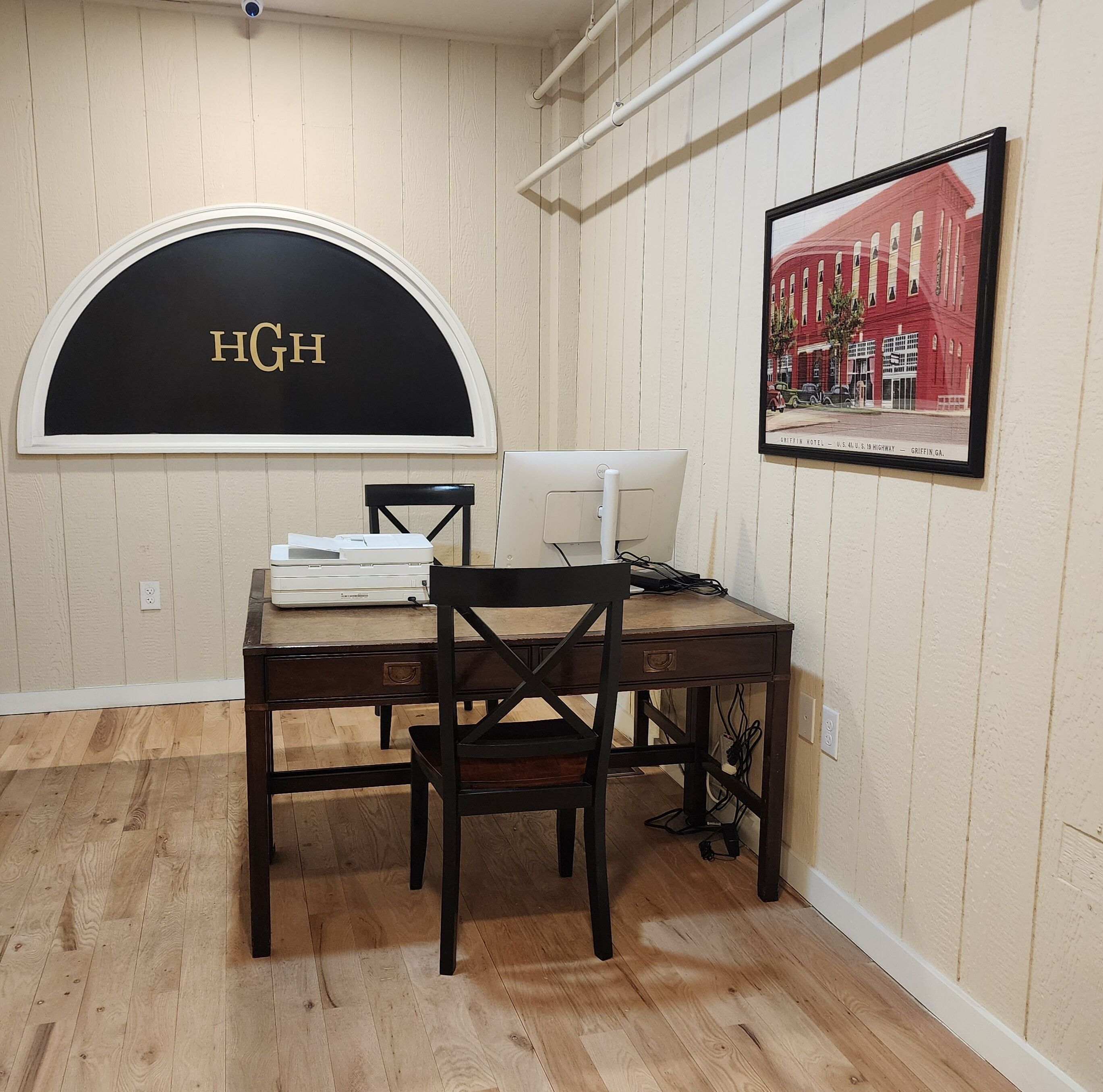 A dining area with a table, chairs, a white desk, and a framed picture on the wall.