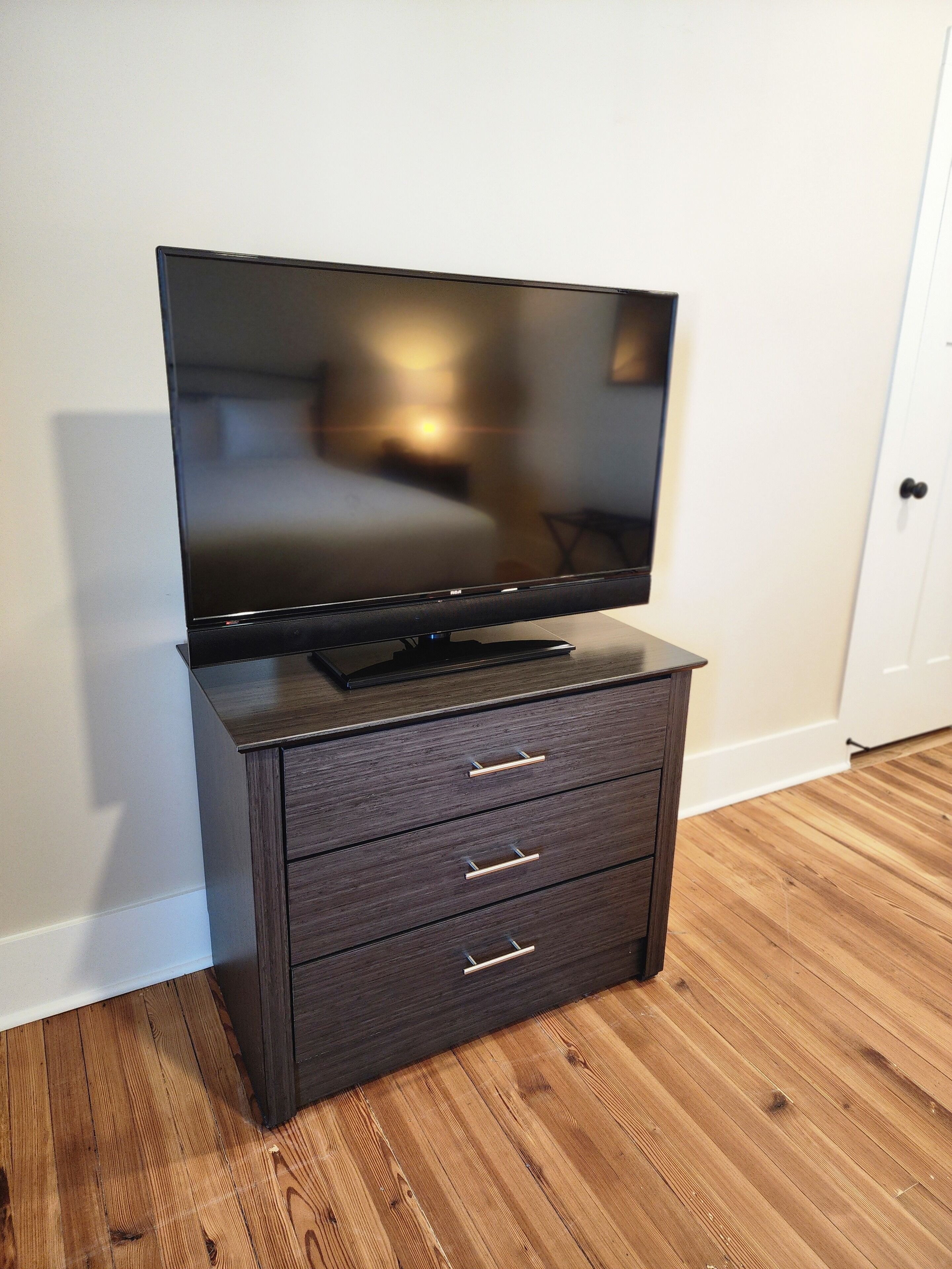 Een donkere houten tv-meubel met een flatscreentelevisie en drie lades.