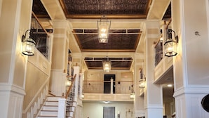 A spacious lobby with a polished floor, a grand staircase, and ornate ceiling details. - Historic Griffin Hotel (Griffin)