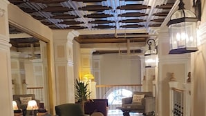 A spacious hallway with wooden flooring, green armchairs, and a decorative ceiling. - Historic Griffin Hotel (Griffin)