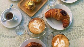 Ein Frühstückstisch mit Croissants, Kaffee und einer Gebäckplatte.