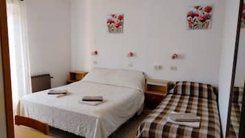 Un dormitorio con dos camas, una mesita de noche de madera, una pequeña mesa y un radiador.