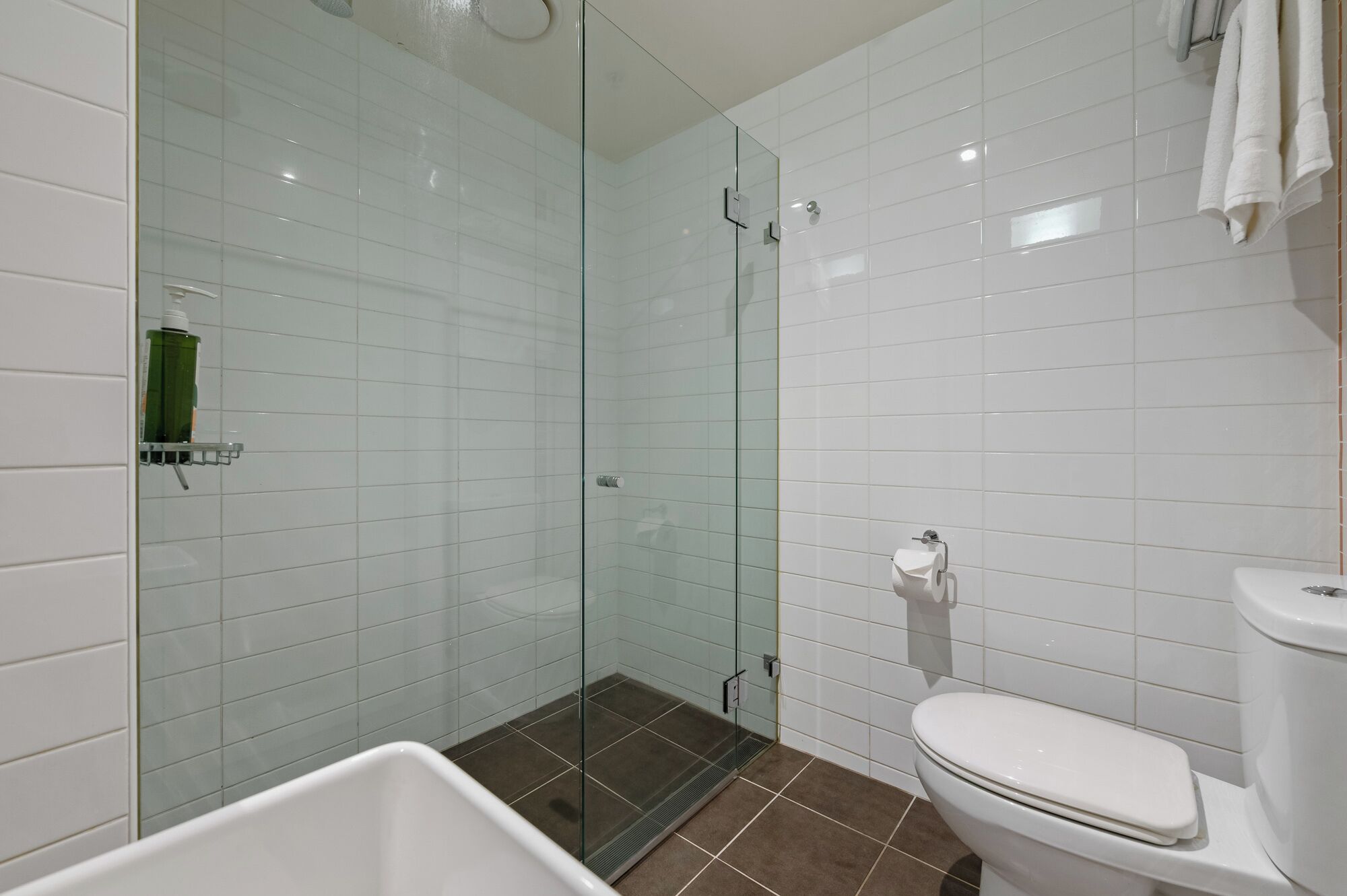 A modern bathroom with a glass-enclosed shower, a white toilet, and a bathtub.