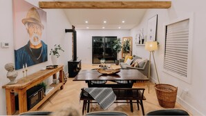 Una sala de estar moderna con una mesa de comedor de madera, un sofá y un cuadro grande.
