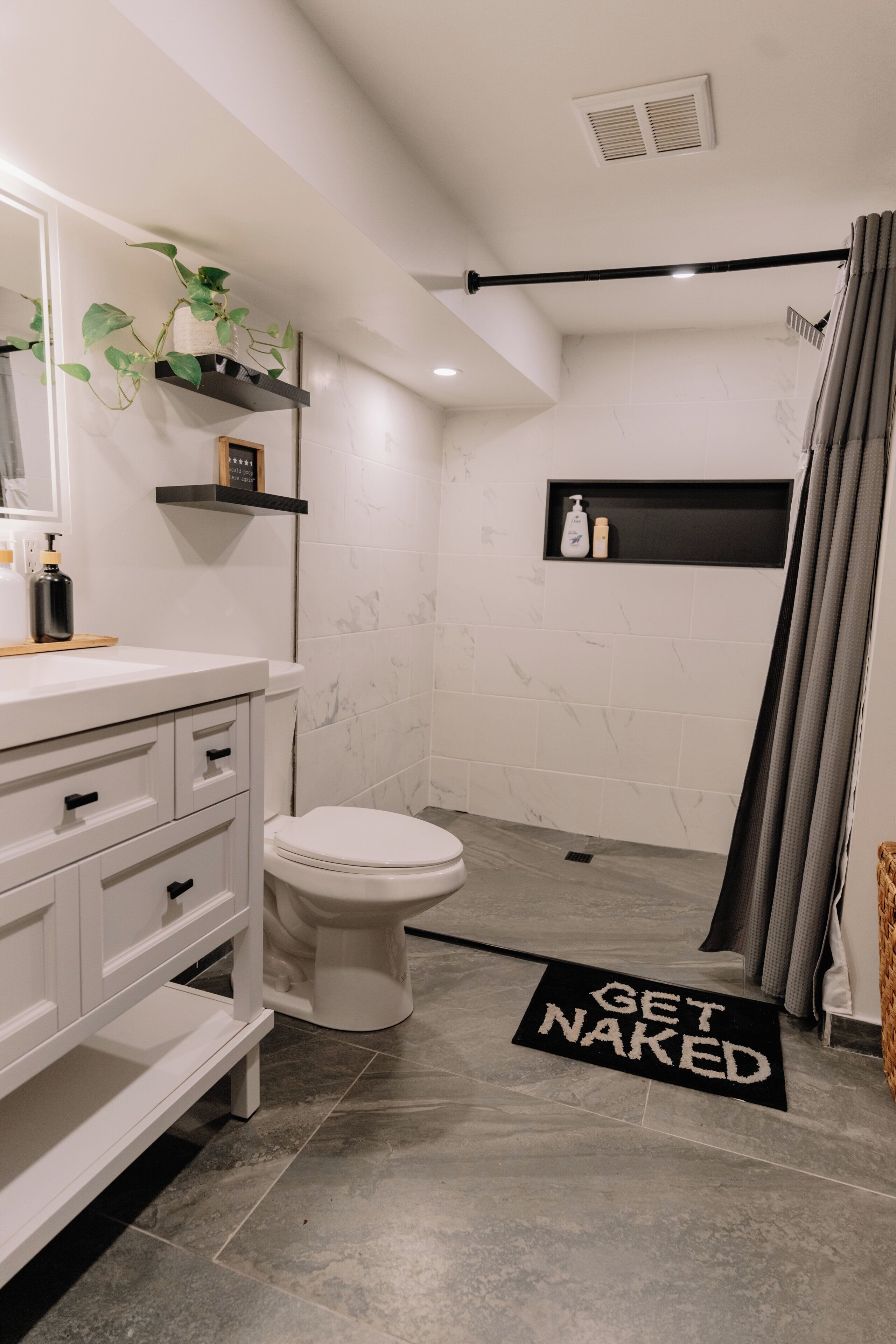 A modern bathroom with a white toilet, a sink with a mirror, and a shower area.
