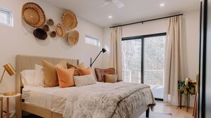 Un dormitorio con una cama grande, una mesita de noche, una lámpara y vistas al exterior.