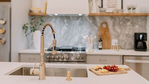 Una cocina moderna con salpicadero de mármol, electrodomésticos de acero inoxidable y tabla de madera con uvas y queso.