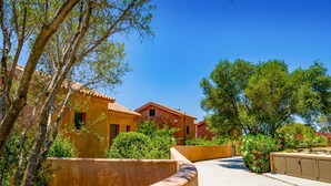 A courtyard with traditional buildings, a curved pathway, and lush greenery. - Rhea Villa in Kefallonia (Kefalonia)