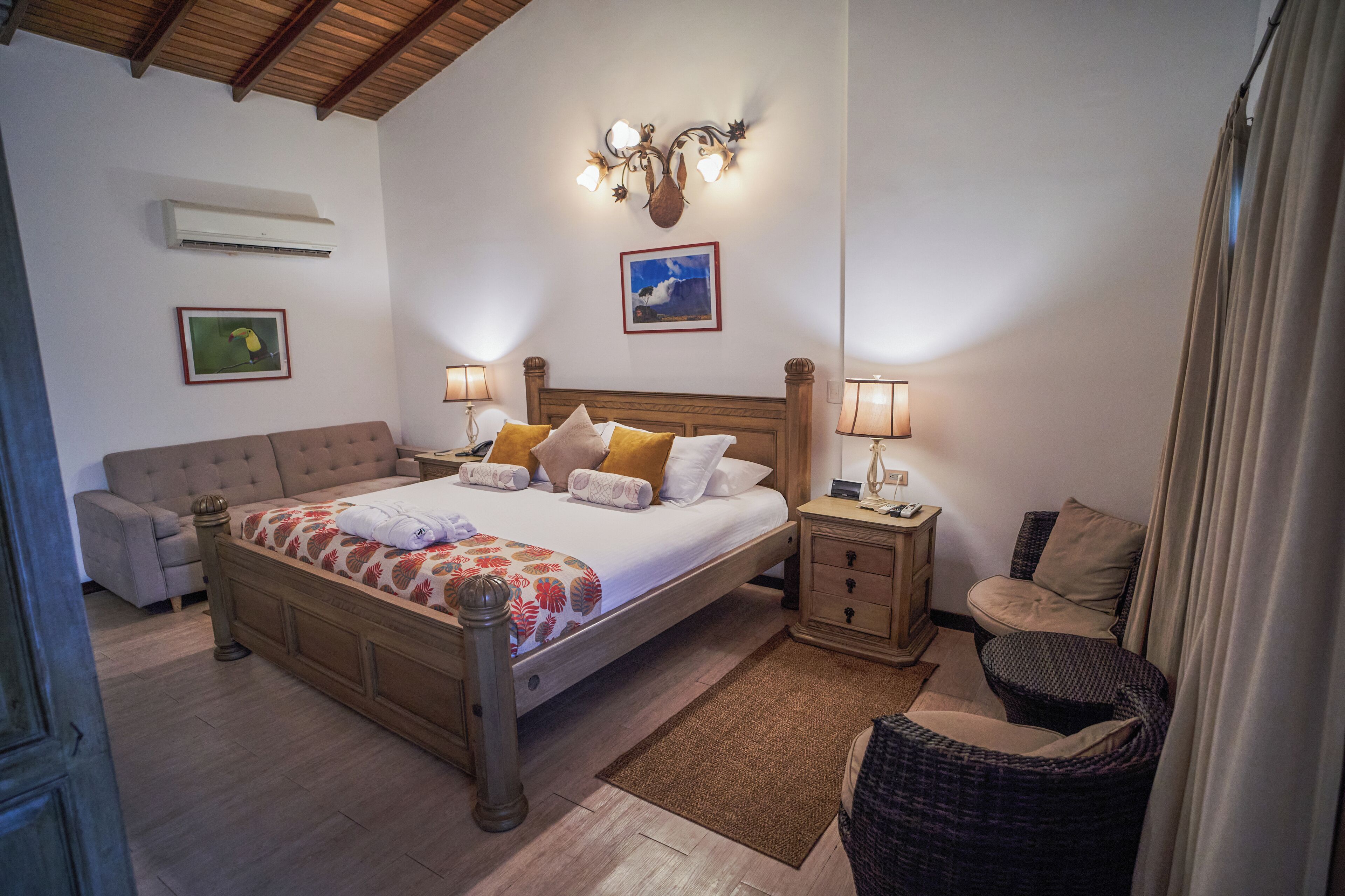 A bedroom with a wooden bed, bedside tables, a nightstand, a chair, and a wall-mounted air conditioner.
