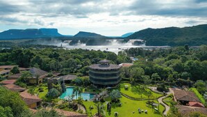 A resort with a central building, a swimming pool, and a waterfall in the background. - Posada Turistica Ara Meru Lodge (Gran Sabana)
