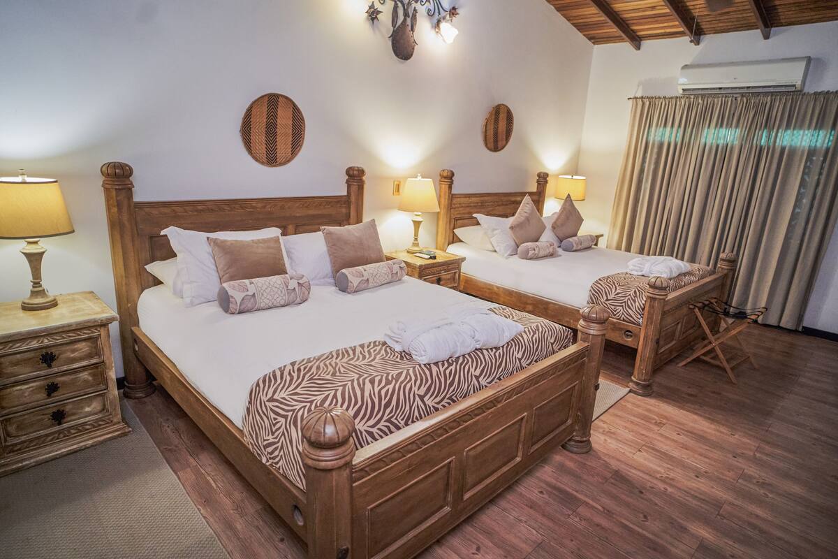 A double bed with a zebra-patterned bedspread, two bedside tables with lamps, and a wooden headboard.