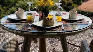 A round glass table set for dining with a view of a waterfall and lush greenery in the background. - Posada Turistica Ara Meru Lodge (Gran Sabana)