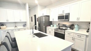 A modern kitchen with white cabinets, a central island, and stainless steel appliances. - Brand new house with heated salt water pool. Perfect get away in Palm Coast (Palm Coast)