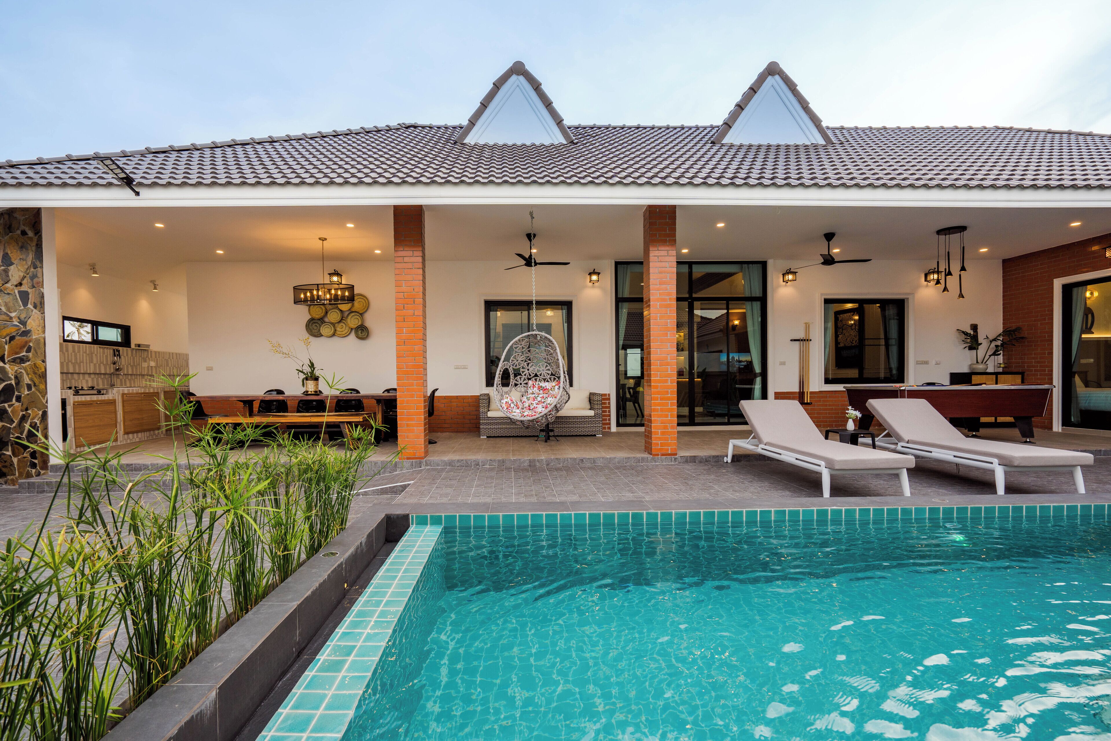 A modern house with a swimming pool, outdoor seating, and a patio area.