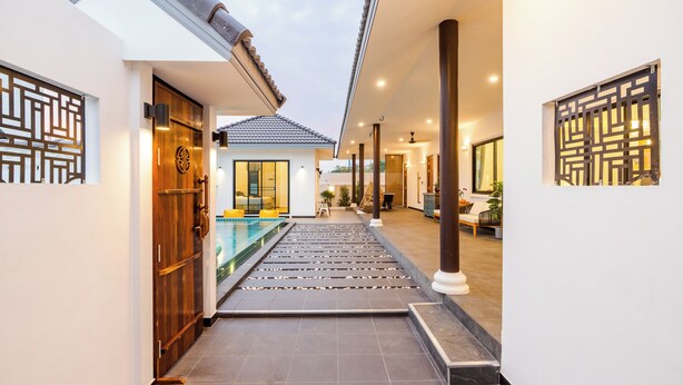A modern hotel corridor with a pool, wooden doors, and traditional decor.