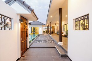 A modern hotel corridor with a pool, wooden doors, and traditional decor.