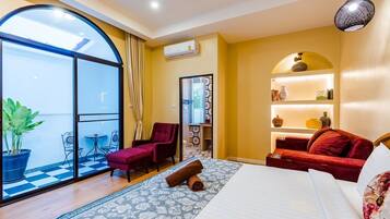 Ein Hotelzimmer mit großem Fenster, einem roten Sofa, einem Bett und einem kleinen Tisch mit Stühlen.