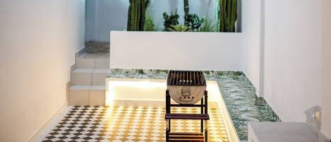 A modern interior with a checkered floor, a white bench, and a cactus garden in the background.