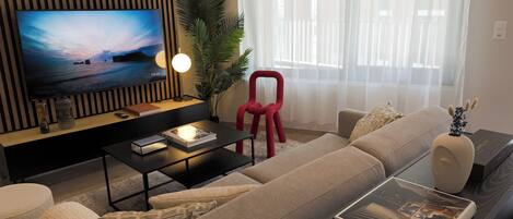 A modern living room with a flat-screen TV, a red chair, a sofa, and a coffee table.