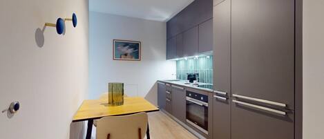 A modern kitchen with grey cabinets, a wooden table, and a chair.