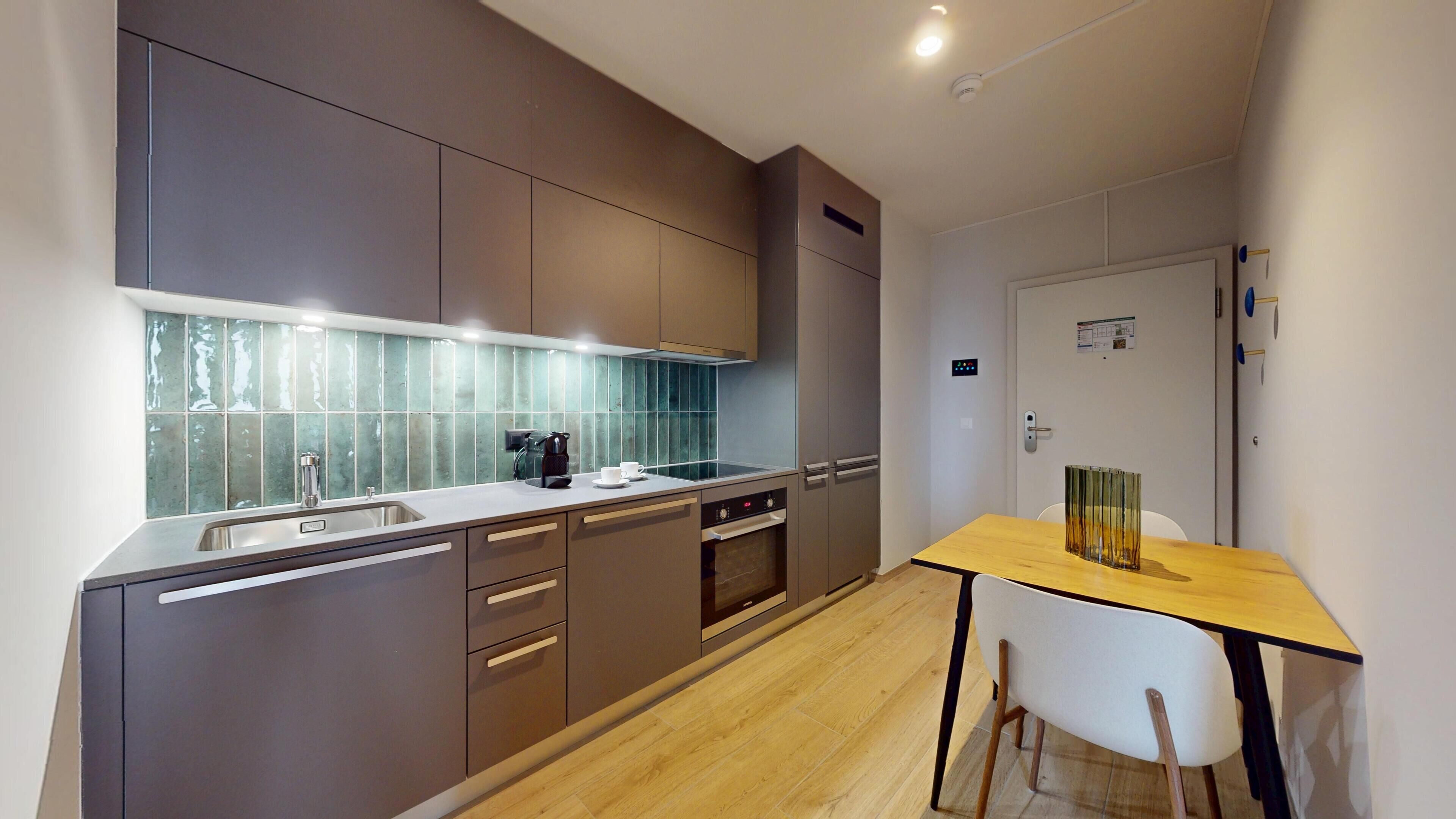 A modern kitchen with grey cabinets, a stainless steel sink, and a wooden dining table with chairs.