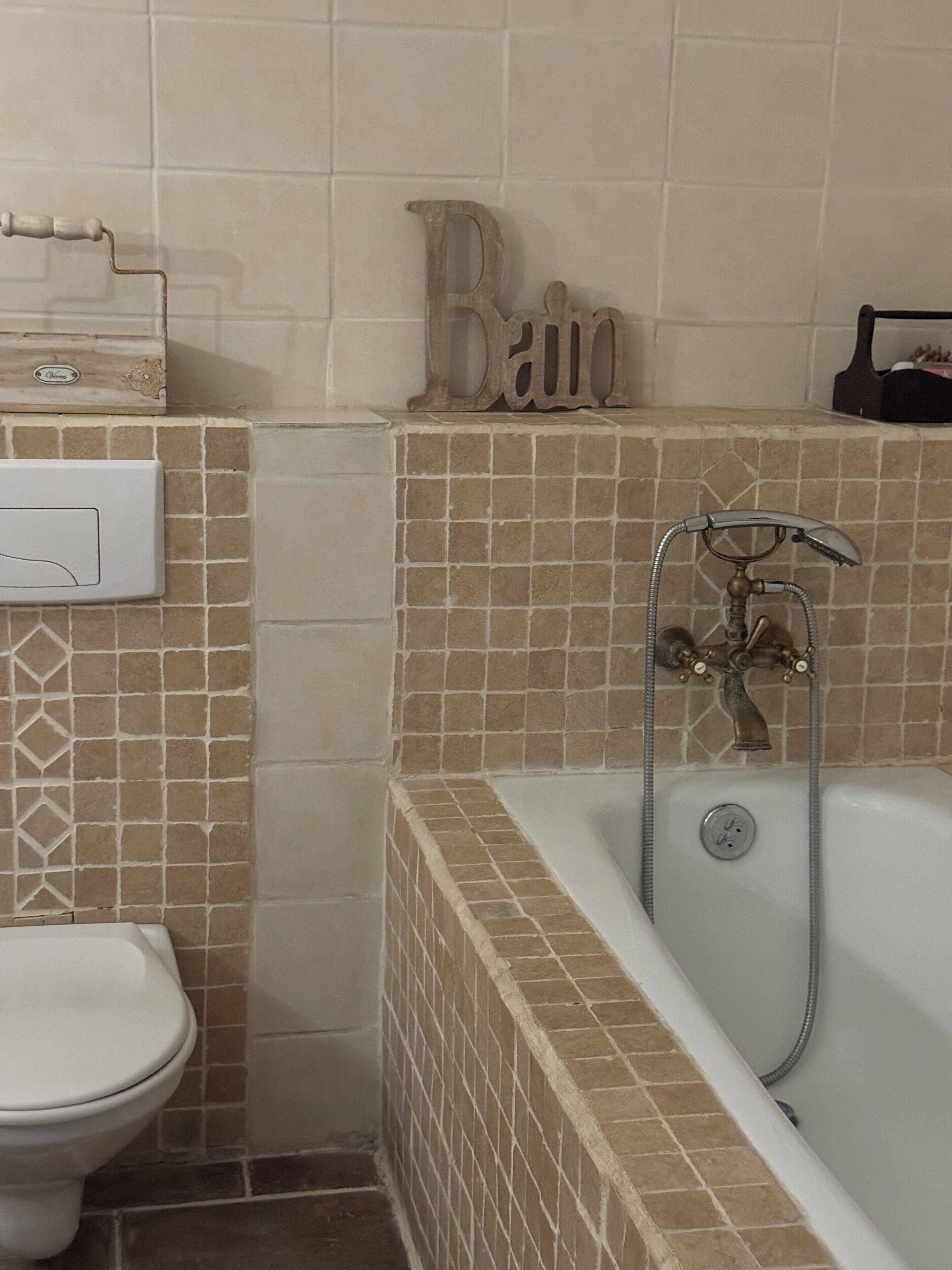 A bathroom with a bathtub, toilet, and a wall-mounted towel rack.