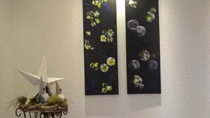 A room with a white wall, a wooden floor, and two paintings depicting flowers and celestial bodies. - Vacation apartment Löwenzahn Müddersheim Vettweiß (Vettweiß)