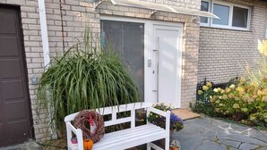 A white bench with a wreath and pumpkins in front of a house with a brick exterior and a white door. - Vacation apartment Löwenzahn Müddersheim Vettweiß (Vettweiß)