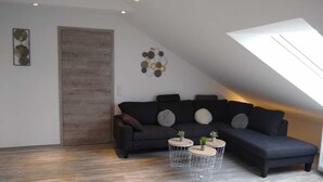 A modern living room with a dark sofa, round coffee tables, and a skylight. - Vacation apartment Löwenzahn Müddersheim Vettweiß (Vettweiß)