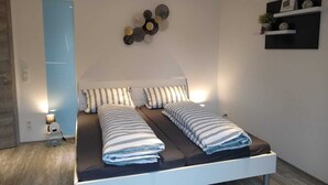 A modern bedroom with a bed, bedside tables, and a wall-mounted decor piece. - Vacation apartment Löwenzahn Müddersheim Vettweiß (Vettweiß)