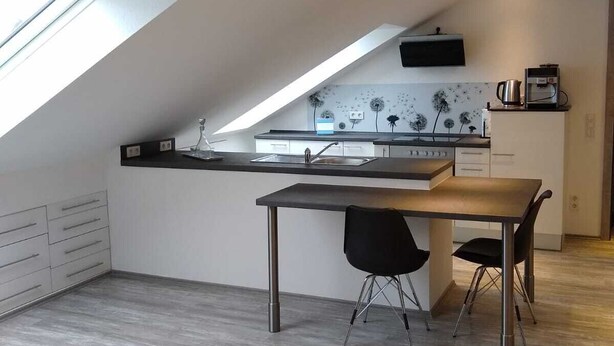A modern kitchen with a skylight, a dining area with a table and chairs, and a small island with a coffee machine. - Vacation apartment Löwenzahn Müddersheim Vettweiß (Vettweiß)