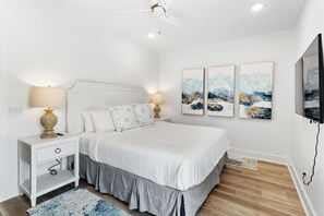 Un dormitorio con cama, mesitas de noche, ventilador de techo y decoración en las paredes.
