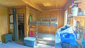 Une petite cabine équipée de lits superposés, d’une kitchenette et d’un intérieur en bois.