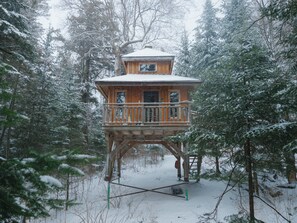 A wooden tower house surrounded by snow-covered trees. - Lakefront treehouse, close to parking | Lodging #03 (Mont-Blanc)