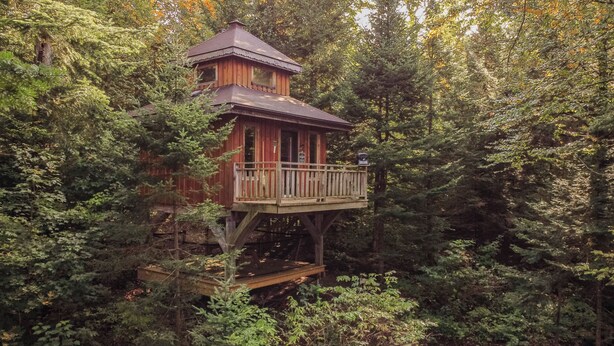 A wooden cabin with a balcony, surrounded by dense forest. - Lakefront treehouse, close to parking | Lodging #03 (Mont-Blanc)