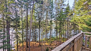 A forested area with a wooden viewing platform overlooking a body of water. - Lakefront treehouse, close to parking | Lodging #03 (Mont-Blanc)