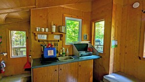 Une cuisine de taille réduite, dotée de meubles en bois, d’un évier, d’une cuisinière et d’une fenêtre donnant sur l’extérieur.