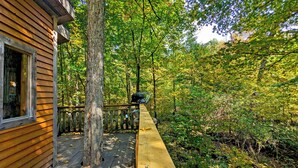 Une cabane en bois dotée d’une terrasse, entourée d’une forêt dense.