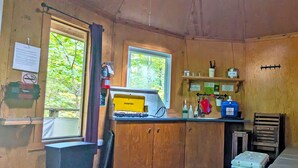 A compact kitchen with wooden cabinets, a sink, and a window with a view of greenery.