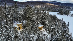 Uma cabana rodeada por árvores cobertas de neve e montanhas.