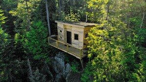 A wooden cabin with a balcony, surrounded by dense forest. - Secluded perched treehouse by the lake | Lodging #18 (Mont-Blanc)