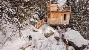 Una cabaña de madera con balcón, ubicada en una montaña nevada.